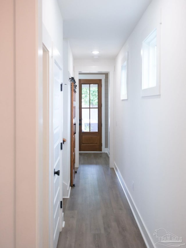 doorway to outside featuring baseboards and dark wood-style floors