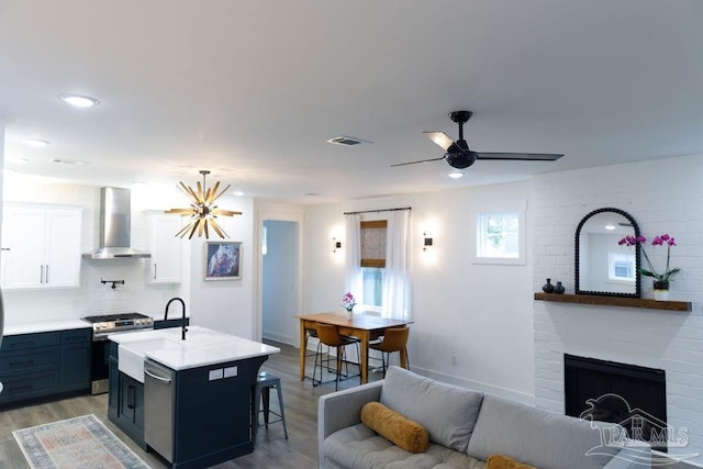 kitchen with visible vents, a sink, stainless steel appliances, wall chimney exhaust hood, and light countertops