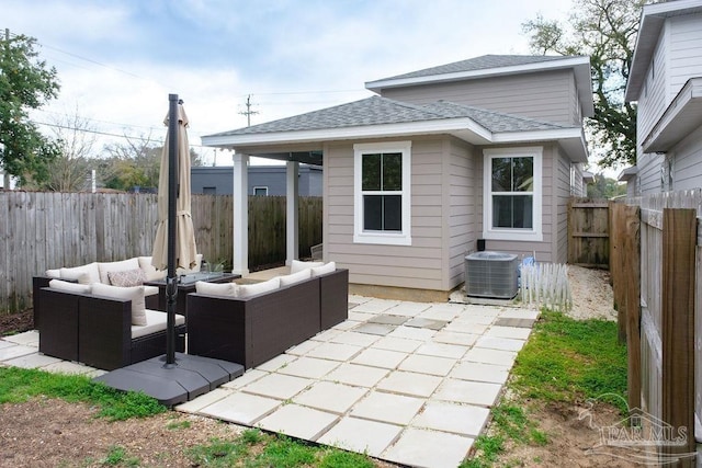 rear view of property with an outdoor living space, central AC, a fenced backyard, roof with shingles, and a patio area