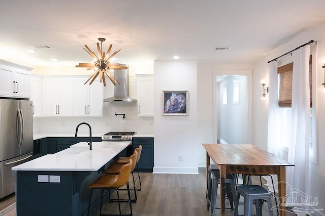 kitchen featuring dark wood-style floors, stainless steel appliances, light countertops, wall chimney exhaust hood, and backsplash