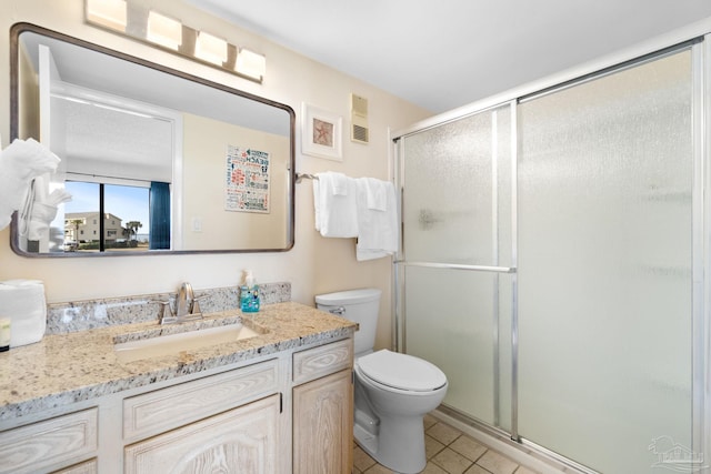 bathroom with tile patterned flooring, vanity, toilet, and walk in shower