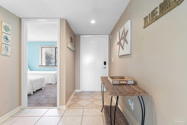 corridor featuring light tile patterned floors and a textured ceiling