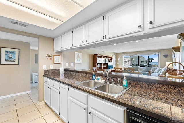 kitchen with white cabinetry, sink, light tile patterned floors, and dishwasher