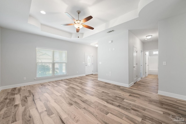 spare room featuring light hardwood / wood-style flooring, a raised ceiling, and ceiling fan