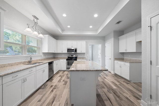 kitchen with a kitchen island, light hardwood / wood-style flooring, sink, white cabinets, and appliances with stainless steel finishes