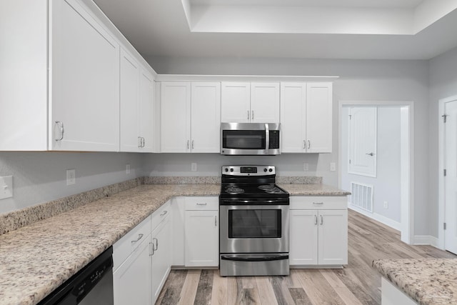 kitchen with appliances with stainless steel finishes, light hardwood / wood-style flooring, and white cabinets