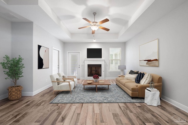 living room featuring hardwood / wood-style floors, ceiling fan, and a raised ceiling