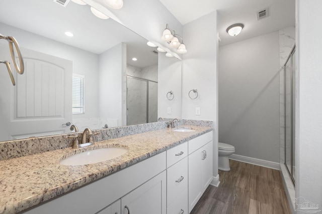 bathroom featuring vanity, wood-type flooring, toilet, and an enclosed shower