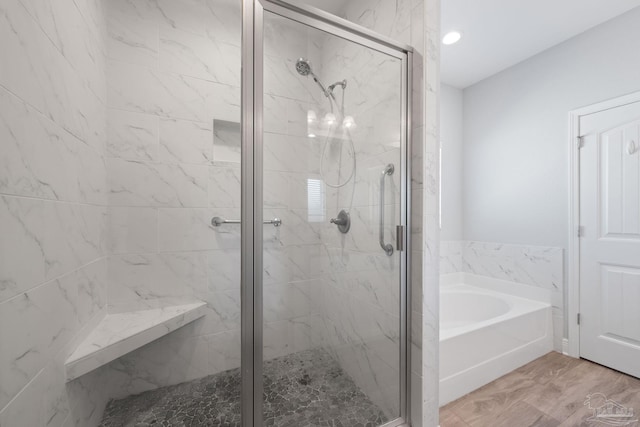 bathroom with hardwood / wood-style floors and independent shower and bath