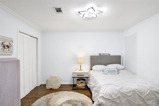 bedroom with a closet, ornamental molding, a textured ceiling, and dark wood-type flooring