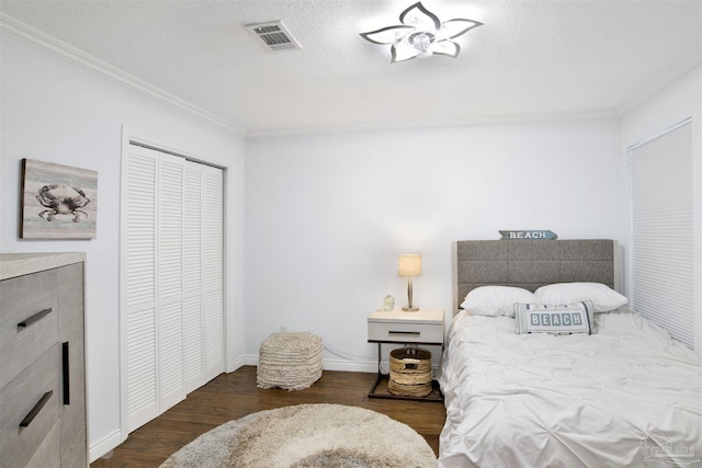 bedroom with a textured ceiling, dark hardwood / wood-style floors, crown molding, and a closet