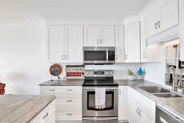 kitchen featuring light stone counters, stainless steel appliances, white cabinetry, and sink