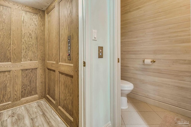 bathroom featuring elevator, toilet, and tile patterned floors