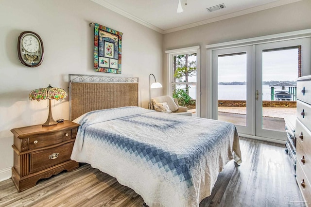 bedroom featuring a water view, wood finished floors, visible vents, access to exterior, and ornamental molding