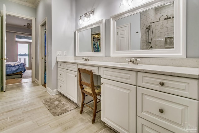 full bath featuring ensuite bathroom, wood finished floors, a sink, tiled shower, and double vanity