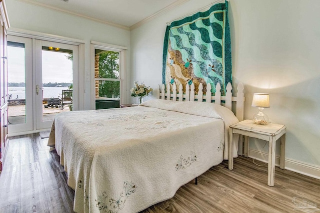 bedroom featuring baseboards, ornamental molding, wood finished floors, a water view, and access to exterior