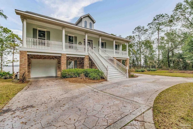 beach home featuring driveway, covered porch, stairs, and brick siding