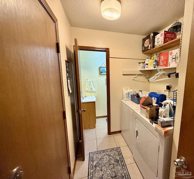 laundry area featuring sink, light tile patterned floors, a textured ceiling, and washer and clothes dryer