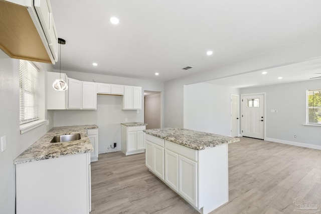 1029 Kearny Dr, Pensacola, FL 32505 - kitchen featuring recessed lighting, light stone counters, a kitchen island, light wood finished floors, and a sink