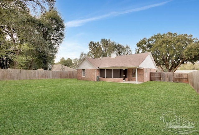 rear view of house with a yard, brick siding, and a fenced backyard