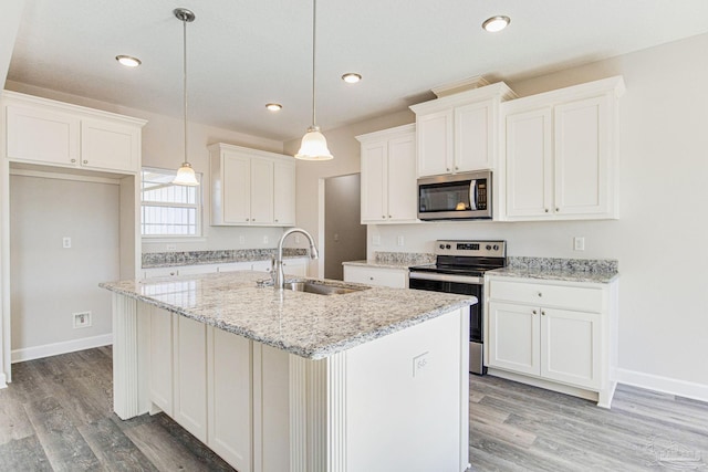 kitchen with a kitchen island with sink, a sink, white cabinetry, appliances with stainless steel finishes, and hanging light fixtures