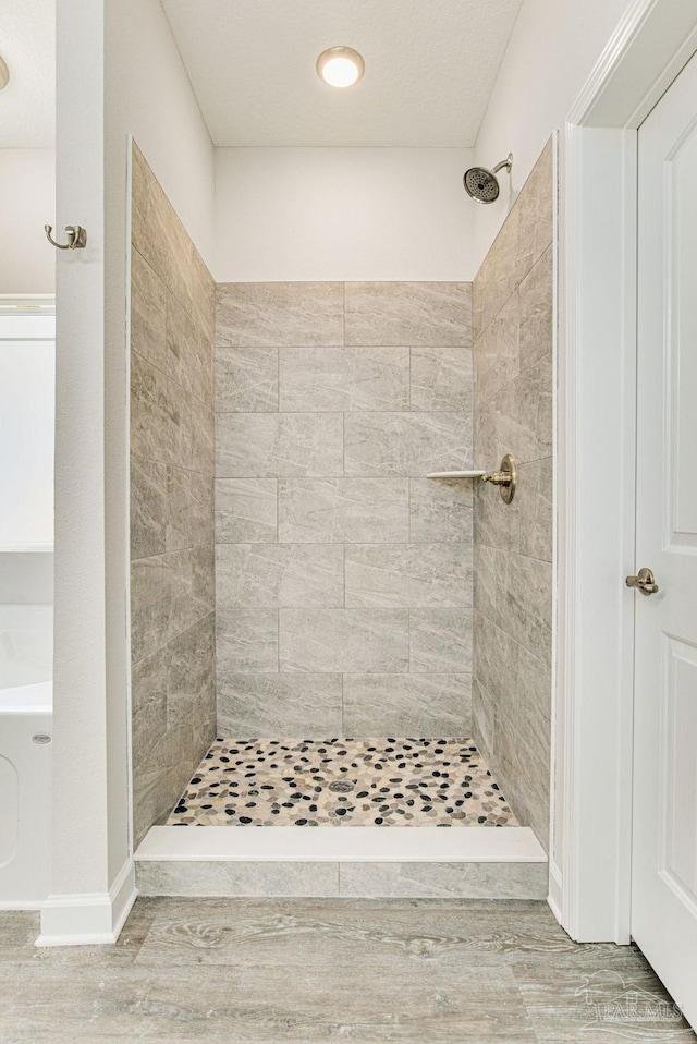 full bath with wood finished floors and tiled shower