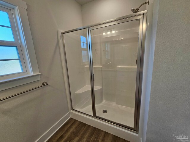 full bathroom with a stall shower, baseboards, and wood finished floors