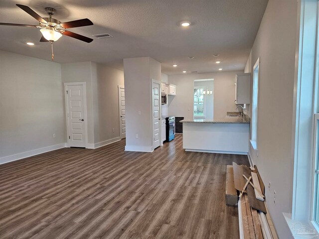 unfurnished living room with baseboards, a textured ceiling, visible vents, and dark wood-style flooring