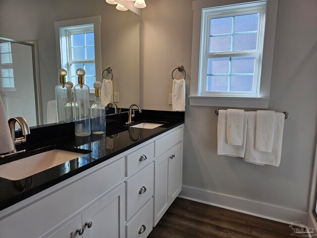 bathroom featuring double vanity, a sink, baseboards, and wood finished floors