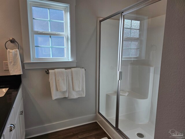 bathroom with wood finished floors, vanity, baseboards, a shower stall, and a wealth of natural light