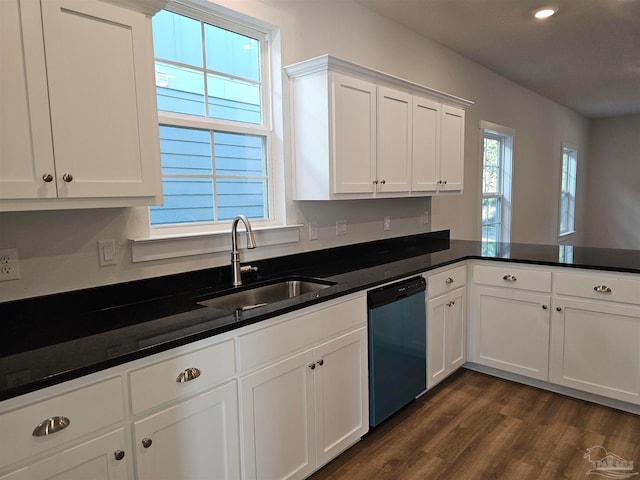 kitchen featuring dark countertops, stainless steel dishwasher, white cabinetry, a sink, and a peninsula