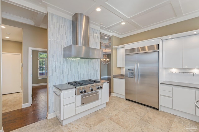 kitchen featuring hanging light fixtures, stainless steel appliances, wall chimney range hood, decorative backsplash, and white cabinets