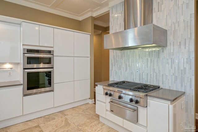 kitchen featuring white cabinets, appliances with stainless steel finishes, wall chimney range hood, and backsplash