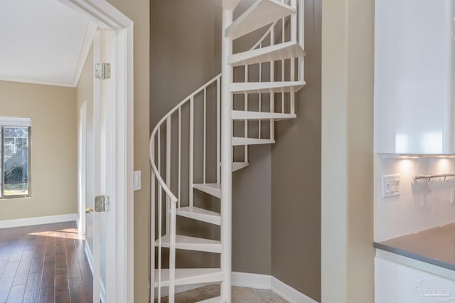 stairway with ornamental molding and wood-type flooring