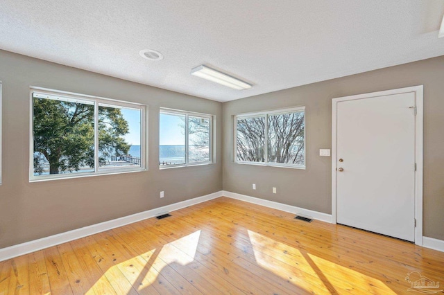 empty room featuring a textured ceiling and light hardwood / wood-style flooring