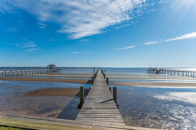 view of dock with a beach view and a water view