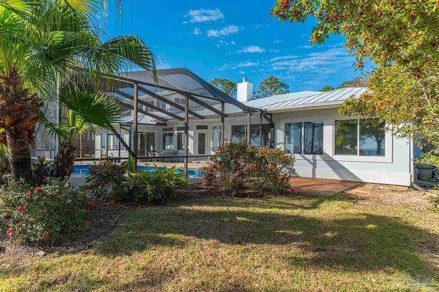 rear view of property featuring a yard and glass enclosure