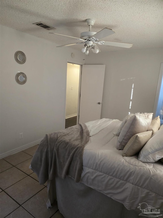 bedroom with ceiling fan, a textured ceiling, and tile patterned floors