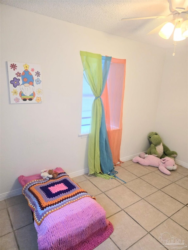 tiled bedroom with ceiling fan and a textured ceiling