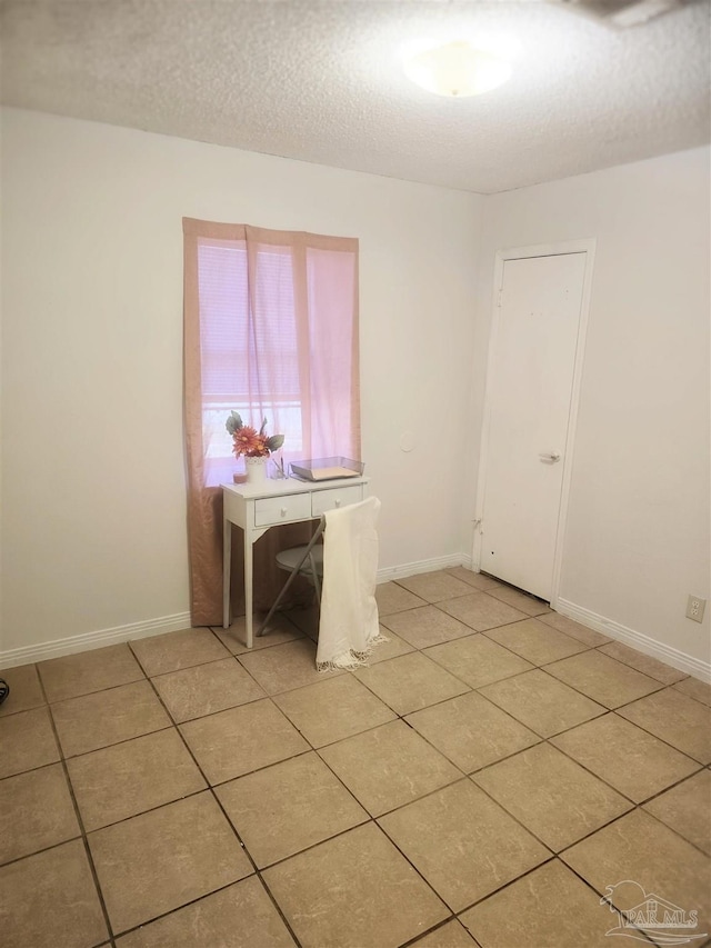 unfurnished dining area featuring a textured ceiling and light tile patterned flooring