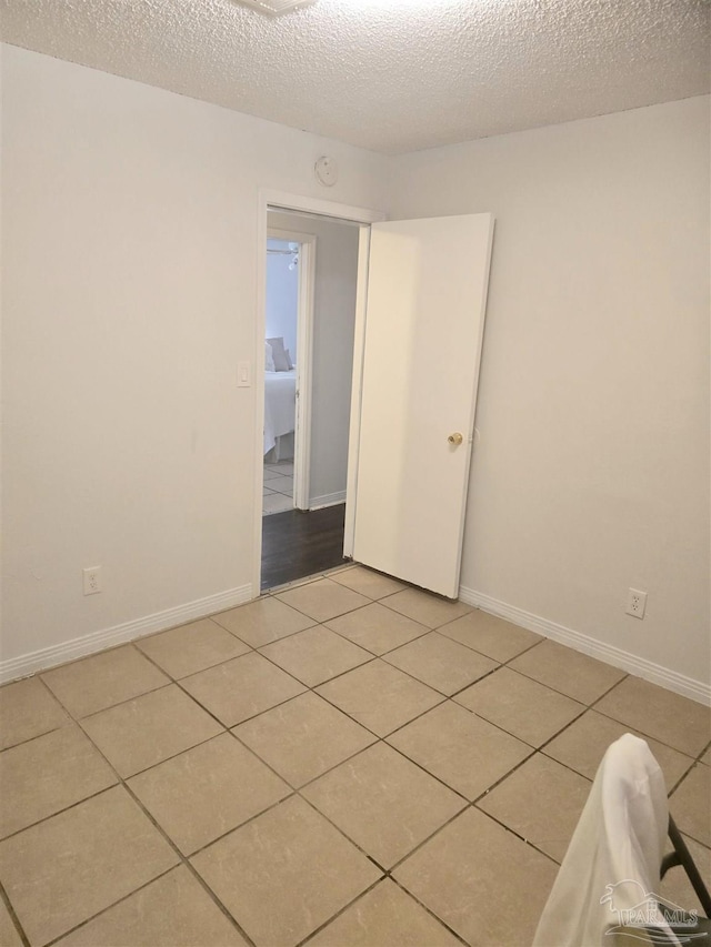 tiled empty room with a textured ceiling