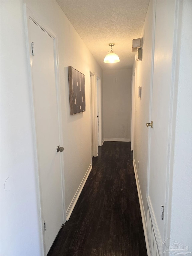 hall featuring a textured ceiling and dark hardwood / wood-style flooring