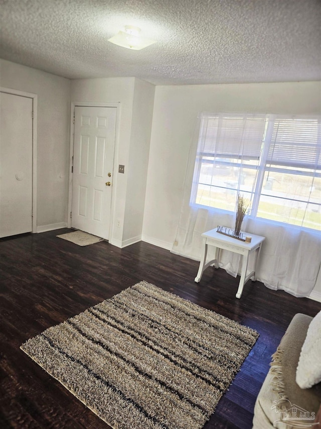 foyer entrance with a textured ceiling and dark hardwood / wood-style flooring