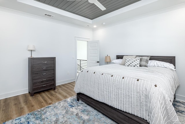 bedroom featuring a tray ceiling, ceiling fan, hardwood / wood-style floors, and ornamental molding