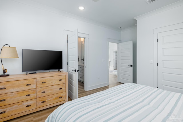 bedroom with wood-type flooring, ensuite bathroom, and crown molding