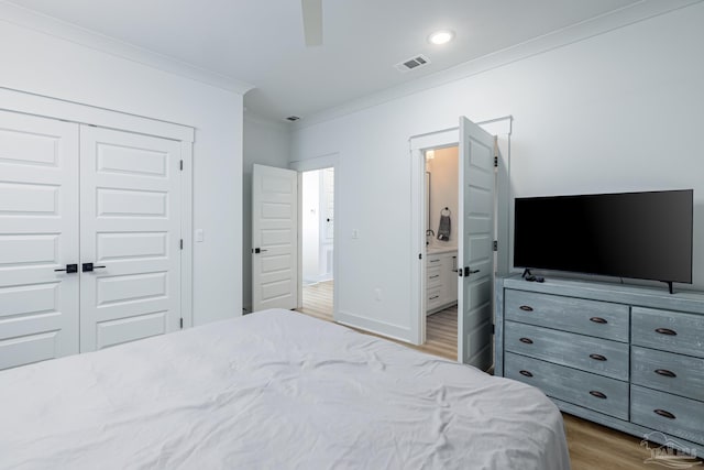 bedroom with connected bathroom, light hardwood / wood-style floors, a closet, and crown molding