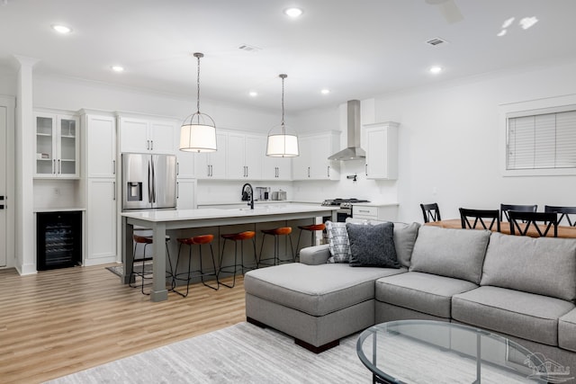 living room featuring light hardwood / wood-style floors, wine cooler, ornamental molding, and sink