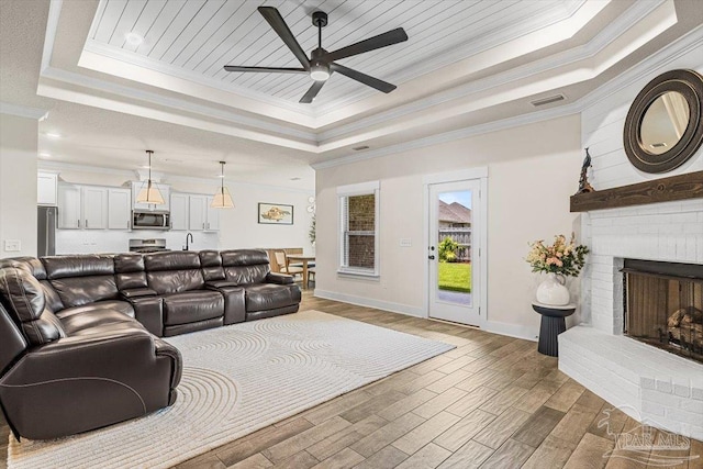 1412 Areca Palm Dr, Gulf Breeze, FL 32563 - living area with a tray ceiling, ceiling fan, crown molding, wood finished floors, and a fireplace