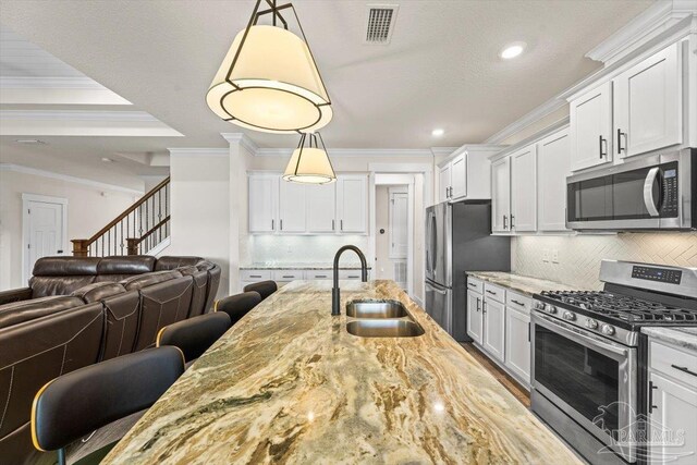 1412 Areca Palm Dr, Gulf Breeze, FL 32563 - kitchen featuring appliances with stainless steel finishes, open floor plan, ornamental molding, light stone counters, and white cabinetry