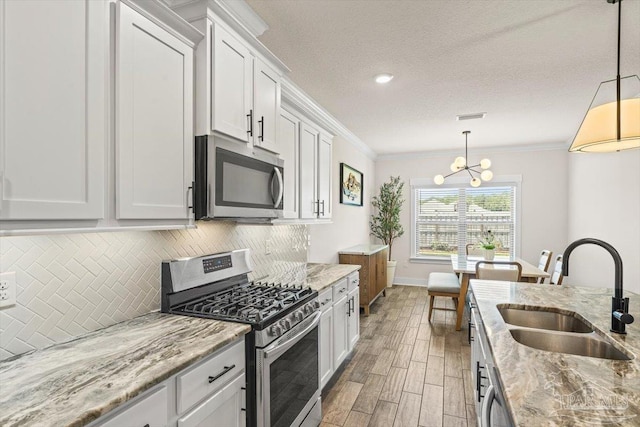 1412 Areca Palm Dr, Gulf Breeze, FL 32563 - kitchen featuring appliances with stainless steel finishes, ornamental molding, backsplash, light wood-type flooring, and white cabinetry
